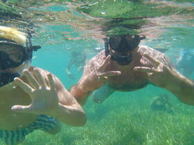 A fun snorkeling adventure captures a child and an adult underwater, showcasing the vibrant marine life and clear waters — perfect for family outings and aquatic exploration.