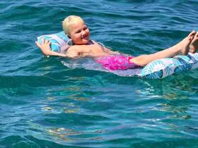 A joyful child floats on a colorful inflatable in crystal-clear waters, capturing the essence of fun and relaxation during a summer day at the beach.