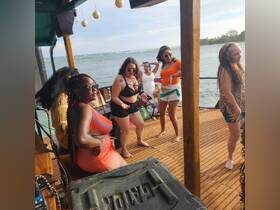 A lively group of friends dances and enjoys their time on a boat, celebrating with drinks and good vibes — perfect for a fun day on the water.