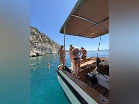 A group of friends enjoys a sunny day on the water, with some swimming and others preparing to join in — perfect for summer adventures and beach outings.
