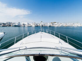 A stunning view from the front of a yacht, showcasing a marina filled with various boats under a clear blue sky — perfect for luxury boating experiences.