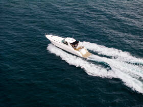 An aerial view of a sleek speedboat cruising through deep blue waters, showcasing its elegant design and dynamic movement.
