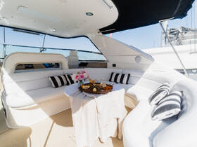 A beautifully arranged interior of a boat featuring elegant seating and a table set with a platter of snacks and flowers, perfect for a relaxing day on the water.