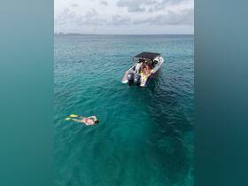 A snorkeler enjoys the clear waters while a group gathers on the boat, showcasing a perfect day of aquatic adventure and fun.