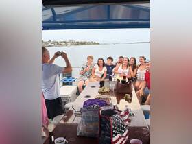 A lively group of friends poses for a photo on a boat, capturing a memorable moment during their outing — perfect for celebrations and fun times on the water.