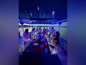 A lively group enjoys a festive boat party, dancing and celebrating under the evening sky — perfect for memorable gatherings on the water.