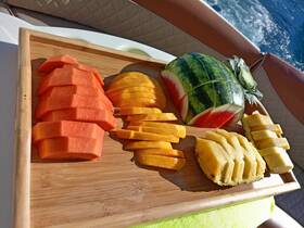 A beautifully arranged platter of fresh tropical fruits, including watermelon, pineapple, mango, and papaya, perfect for enjoying on a boat trip.