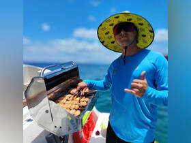 A chef grills delicious food on a boat, showcasing onboard amenities perfect for a fun day at sea.