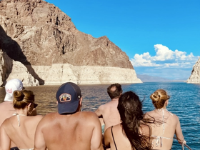 A group of friends enjoys a scenic boat ride on a lake, surrounded by stunning mountain views — perfect for adventure and exploration.