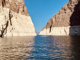 A stunning view of towering cliffs flanking a serene waterway, showcasing the natural beauty of the landscape — perfect for scenic boat tours.