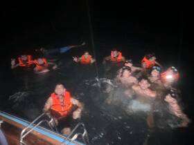 A lively group enjoys a night swim, wearing life jackets and having fun in the water — a memorable experience under the stars.