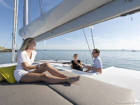 A group enjoys cocktails on the deck of a yacht under a clear blue sky, perfect for relaxing and celebrating special moments on the water.