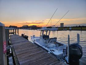 A serene view of a speedboat docked at sunset, showcasing its sleek design against a picturesque waterfront backdrop.