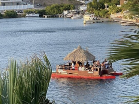A lively group enjoys a festive gathering aboard a tiki-style boat, perfect for celebrations on the water.
