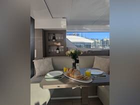 An inviting dining area inside a yacht, featuring a beautifully set table with fresh bread and drinks, perfect for enjoying meals while cruising.