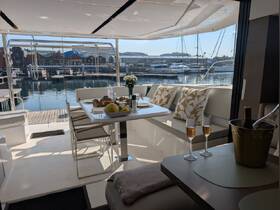A beautifully arranged dining area inside a yacht, featuring elegant seating and a view of the marina — perfect for enjoying meals while on the water.