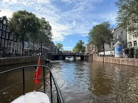 A scenic view of a canal in Amsterdam, showcasing the vibrant city life and architecture, with a boat navigating through the water.