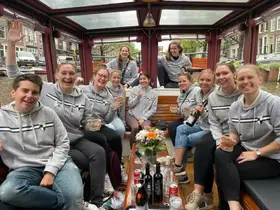 A lively group of friends enjoys a boat tour, celebrating with drinks and smiles, perfect for memorable outings in the city.