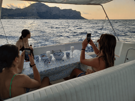 A group of friends enjoys drinks and captures memories aboard a yacht during a beautiful sunset — perfect for social gatherings and celebrations on the water.