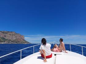 A couple enjoys a serene moment on the bow of a boat, taking in the stunning ocean views and coastal scenery — perfect for a relaxing day on the water.