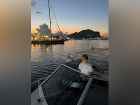 A serene evening view from the helm of a boat, with a person at the controls as the sun sets over the harbor, creating a picturesque backdrop.
