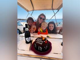 A joyful family celebrates a birthday aboard a boat, complete with a delicious cake and sparkling drinks, creating unforgettable memories on the water.