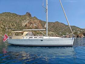 A beautiful sailboat anchored in calm waters, showcasing its elegant design against a scenic backdrop of rocky hills.