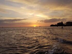 A stunning sunset over the water, with gentle waves reflecting the golden hues — a perfect backdrop for evening boat cruises.