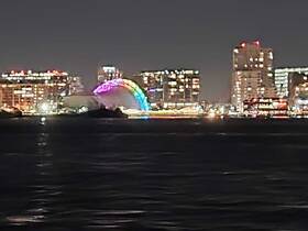 A nighttime view of a vibrant cityscape with illuminated buildings and a colorful arch, creating a picturesque urban scene.