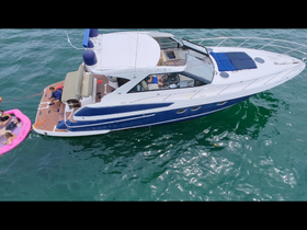 A lively group enjoys a fun day on the water, relaxing on a pink float while anchored next to a stylish yacht — perfect for summer adventures and family outings.