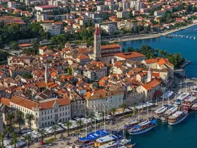 A stunning aerial view of a picturesque coastal town, showcasing charming architecture and a bustling harbor filled with boats — perfect for exploring the beauty of the Adriatic Sea.