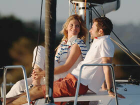 A couple enjoys a romantic moment aboard a sailboat, basking in the warm glow of sunset — perfect for intimate getaways on the water.