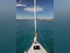A woman enjoys the sun while sailing on a beautiful turquoise ocean, capturing the essence of a perfect day on the water.