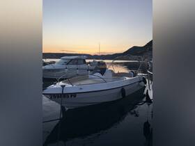 A serene view of a boat docked at sunset, showcasing its sleek design against a picturesque backdrop of mountains and calm waters.