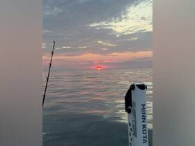A serene sunset view over calm waters, perfect for fishing enthusiasts. The tranquil scene captures the essence of a peaceful evening on the boat.