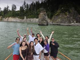 A joyful group of friends poses on the deck of a boat, celebrating their adventure amidst stunning coastal scenery.