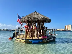 A lively group of friends enjoys a fun day on a tiki boat, celebrating in the sun with drinks and laughter in a beautiful tropical setting.