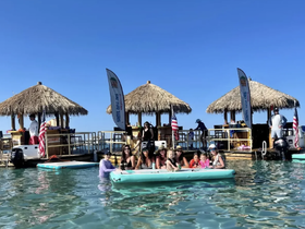 A joyful group enjoys a fun day in the water near tiki huts, perfect for family gatherings and celebrations under the sun.
