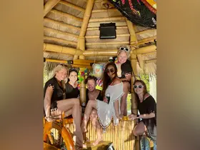 A lively group of friends enjoys a fun moment together in a tiki hut, perfect for celebrations and gatherings on the water.