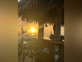 A serene sunset view from a tropical bar setting, capturing the essence of relaxation by the water.