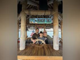 A family poses at the helm of a tiki boat, enjoying a fun day on the water — perfect for creating lasting memories together.