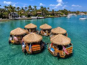 A stunning aerial view of tiki boats anchored in clear turquoise waters, showcasing a unique and vibrant boating experience in a tropical setting.