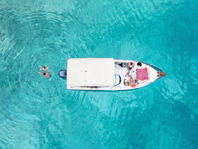 A lively scene captures a group enjoying snorkeling in crystal-clear turquoise waters, with a boat providing the perfect backdrop for a fun day on the water.
