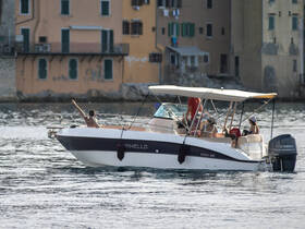 A group enjoys a sunny day on a Marinello boat, waving and celebrating while cruising through calm waters — perfect for summer outings.