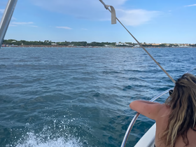 A guest enjoys the view from the bow of a boat, with a picturesque coastline in the background — perfect for a day of exploration on the water.