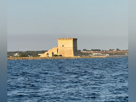 A picturesque view of a historic tower along the coastline, captured from the water — a stunning landmark perfect for sightseeing during boat tours.