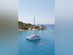 A lively group enjoys snorkeling around a beautiful catamaran anchored near a picturesque island, showcasing the perfect day on the water.
