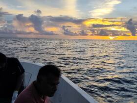 Two individuals enjoy a stunning sunset on the ocean, creating a picturesque backdrop for a memorable boating experience.