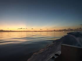 A serene sunset view from a boat, showcasing calm waters and a beautiful horizon — perfect for evening cruises.