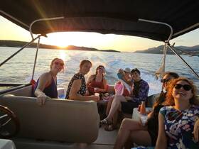A joyful group of friends enjoys a sunset cruise on a boat, capturing the essence of fun and camaraderie on the water.